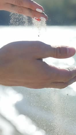hand pouring sand into water