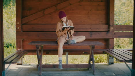 mujer joven escribiendo en un diario sentada en la mesa