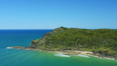 Beautiful-Green-Headland-Surrounded-By-Turquoise-Ocean-Waves