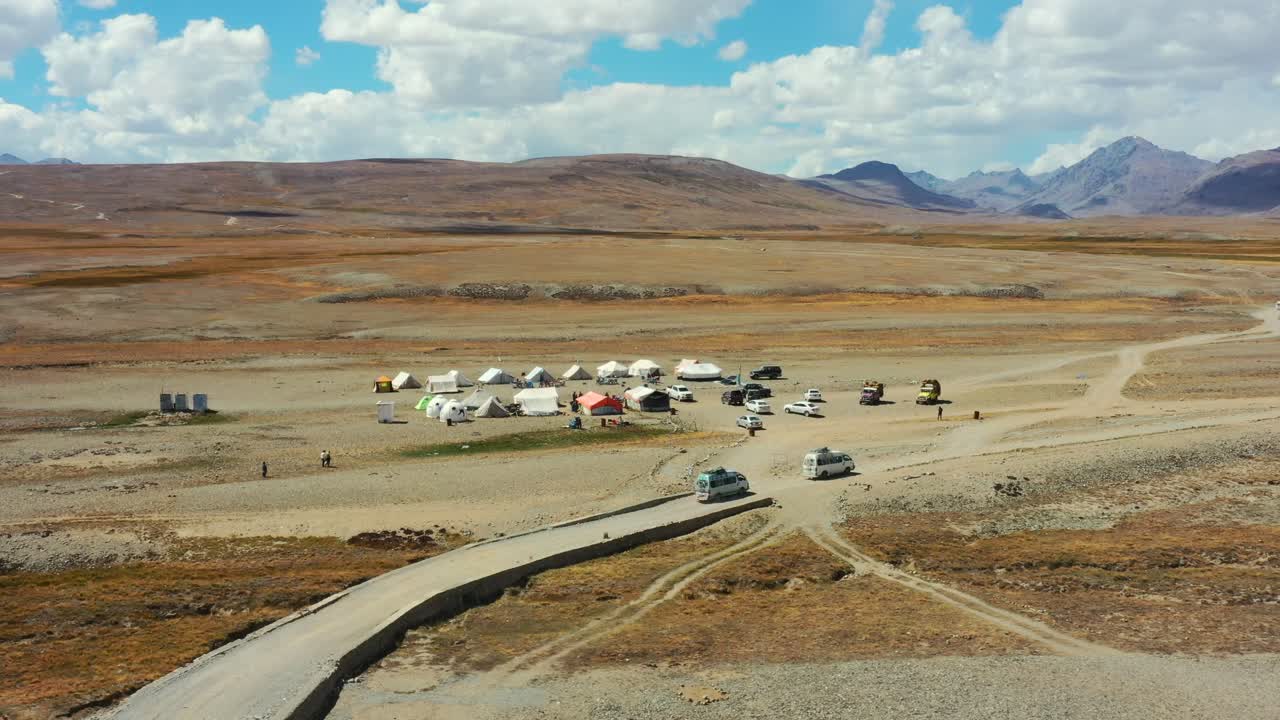화창한 날 파키스탄의 스카르두와 아스토어 계곡 사이에 위치한 데오사이 국립공원의 고산 평원에 있는 캠프장에 도착하는 화물과 관광객을 운반하는 밴의 공중 드론