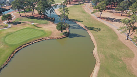 aerial flyover empty myrtlewood golf course with lake during sunny day in myrtle beach