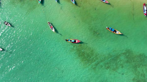 Orbit-aerial-drone-shot-of-the-Rawai-Beach-with-its-white-sandy-beach,-crystal-clear-emerald-waters,-and-the-famous-Thai-long-tailed-boats,-located-in-the-island-of-Phuket-in-Southern-Thailand