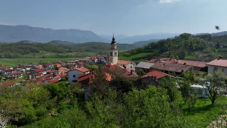 scenic vipava village with church steeple and vineyards in slovenia, aerial pull-back