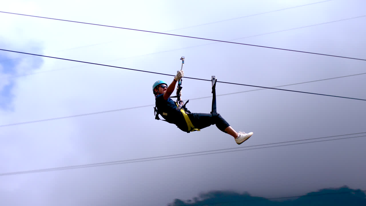 Slomo of young man riding zip line at Ba&ntilde;os in Ecuador, tracking pan