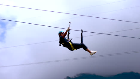 slomo of young man riding zip line at baños in ecuador, tracking pan