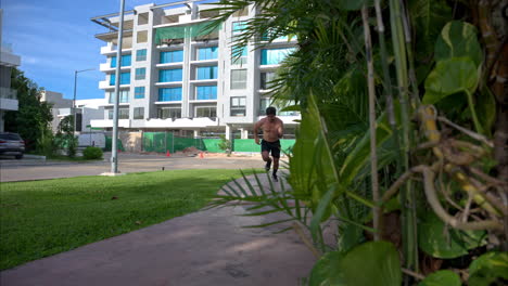 panorámica en cámara lenta de un joven hispano corriendo sin camisa frente a la cámara en un día soleado y brillante