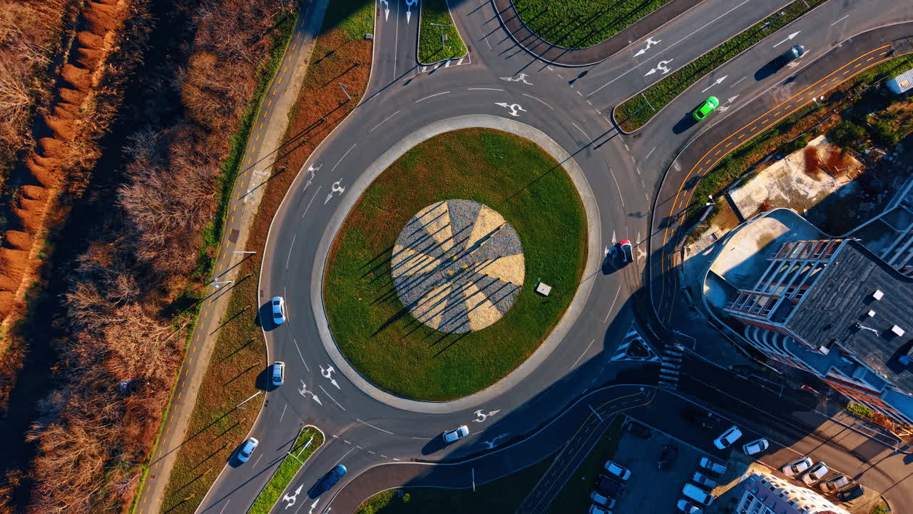 Aerial top view of modern city traffic roundabout intersection. Top down drone shot of circular road junction with cars and shadows