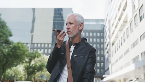 hombre caucásico por la calle de la ciudad hablando en su teléfono inteligente