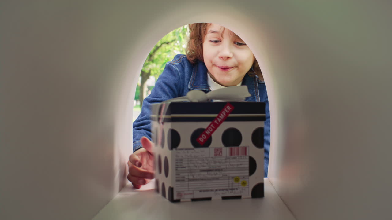 Excited Boy Taking Gift Box out of Mailbox and Jumping Outdoors
