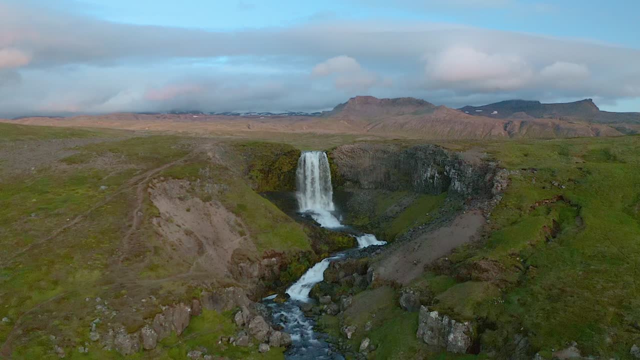Approaching aerial of a waterfall in Iceland on a summer day