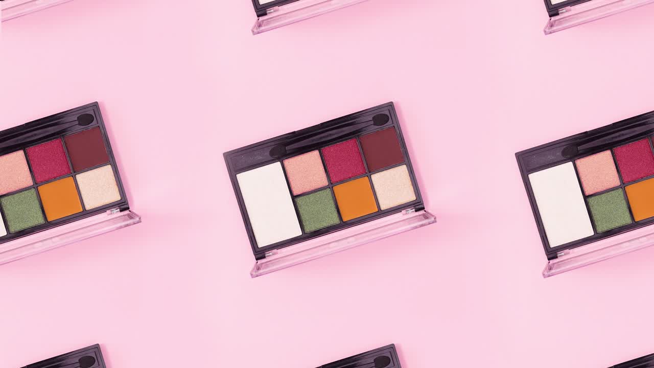 colorful eye shadow palettes rotating on bright pink background. Stop motion