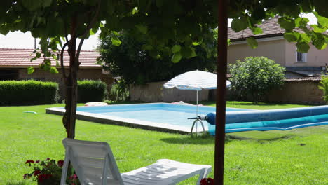cozy backyard with a pool, lounge chair, and umbrella on a sunny day