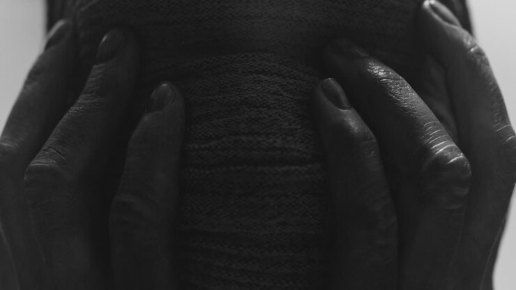 A mummified woman against the bright background in keeps her hands on her face the powerful pose full of despair