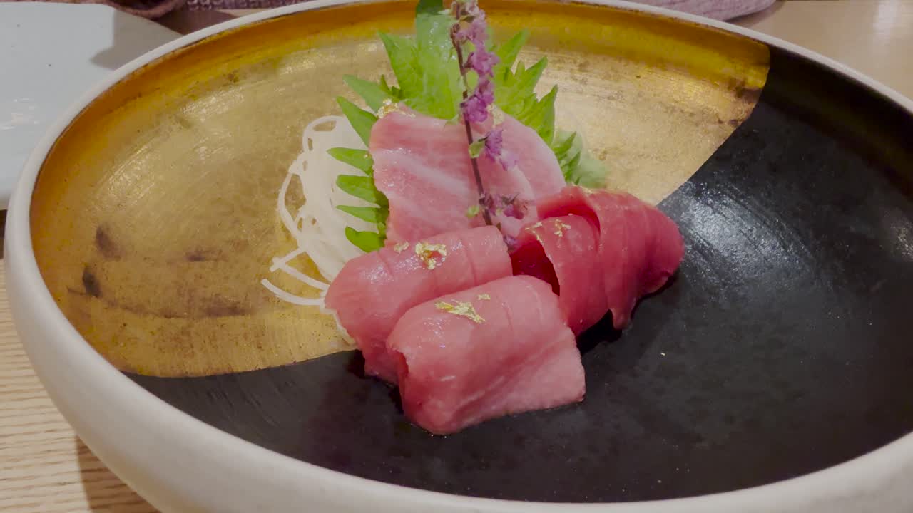 Sashimi di tonno rosso su un piatto elegante guarnito con foglia d'oro. Tavolo da ristorante