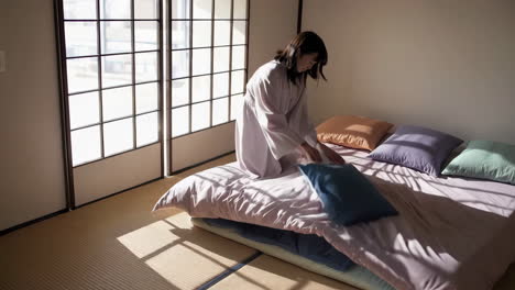 woman arranging futon on tatami mat bedroom