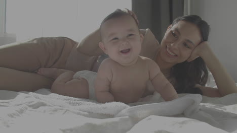 cute smiley happy baby and mom laying in bed