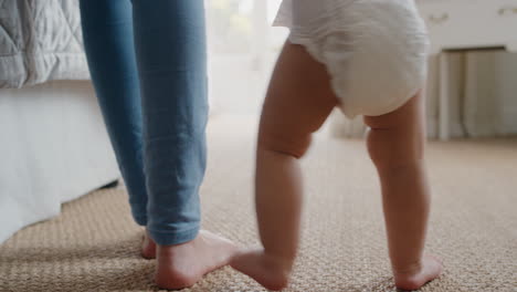 baby taking first steps toddler learning to walk with mother gently helping infant teaching child at home motherhood trust