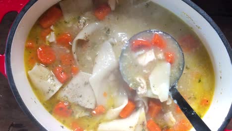 closeup-stirring-of-large-cast-iron-pot-of-homemade-chicken-and-dumplings-with-carrots-with-ladle-scoop-with-lots-of-steam