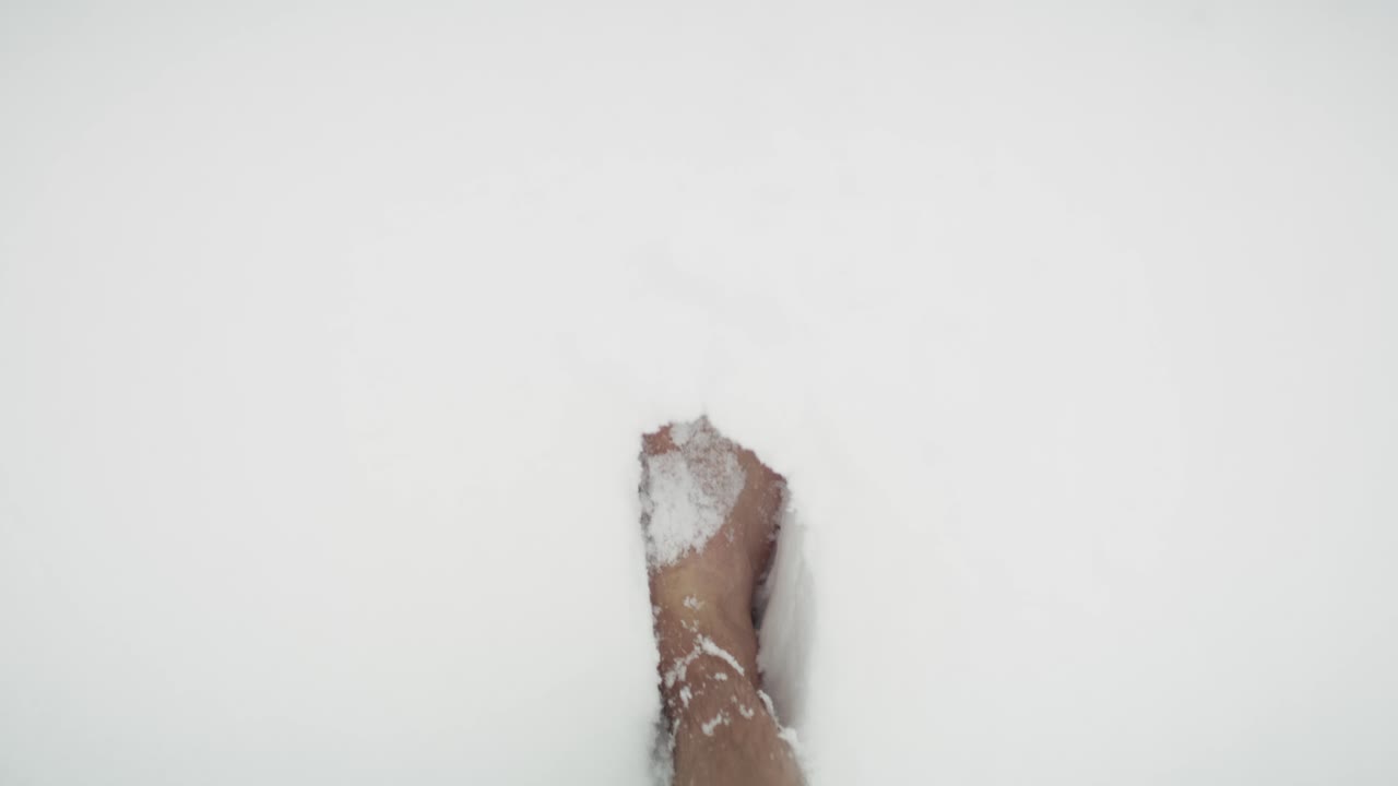 hombre caucásico caminando descalzo en la nieve pov