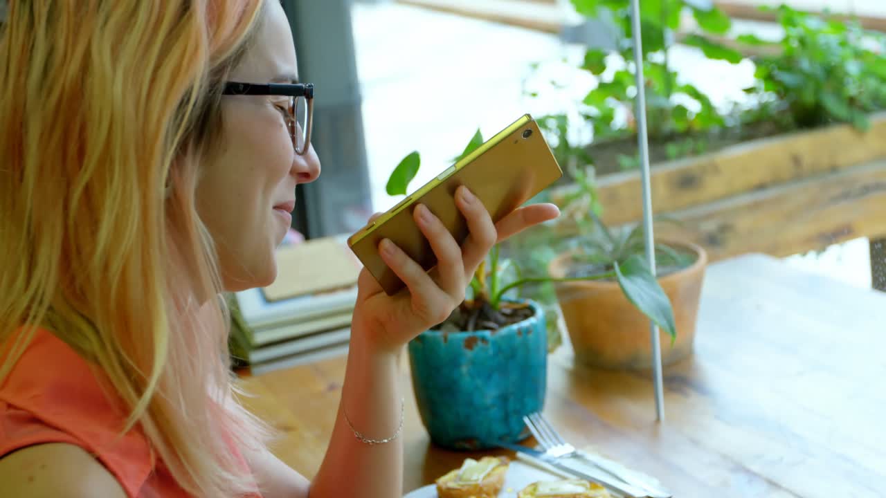 mujer joven hablando por teléfono mientras estaba sentada en el café 4k