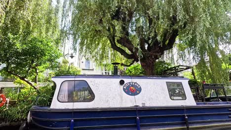 narrowboats moving along a tree-lined canal