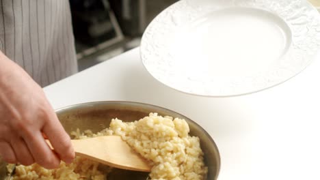 cook serving parmesan risotto on plate