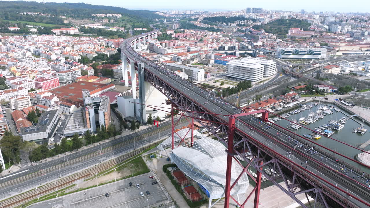 Half marathon and 10K long-distance running event in Lisbon, Portugal, Europe. Runners on the 25th April bridge running to the Águas Livres aqueduct. Alcantara, Monsanto park, aerial drone shot