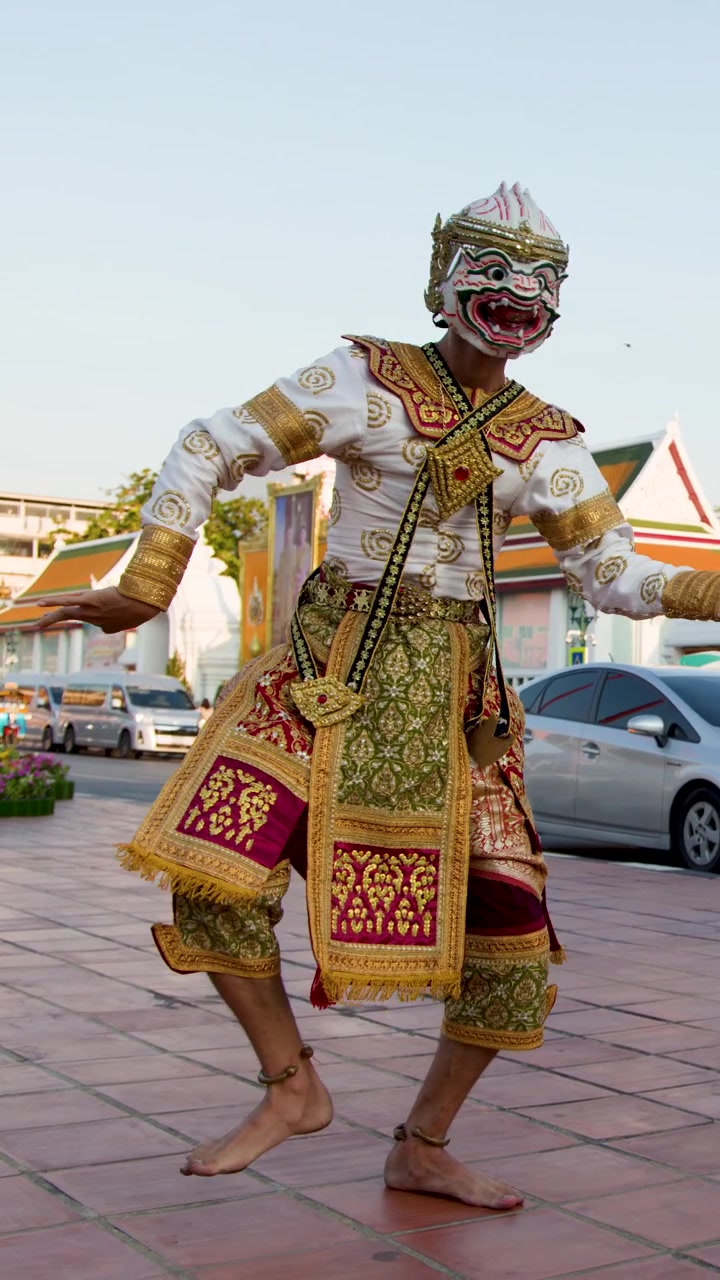 Seorang penari Khon bertopeng menampilkan gerakan tradisional dengan kostum mewah di luar kuil Bangkok