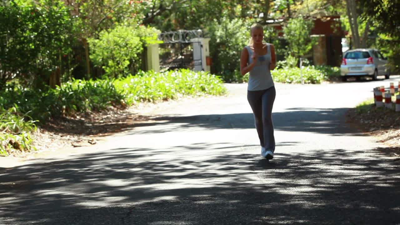 Jogging woman runs down the street with the camera in front of her