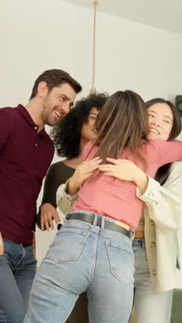 multiethnic group of friends embracing happily and celebrating in apartment