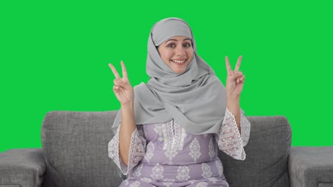 mujer musulmana feliz mostrando el signo de la victoria pantalla verde