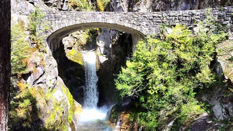 small waterfall flowing under under a stone bridge in north cascade national park, usa