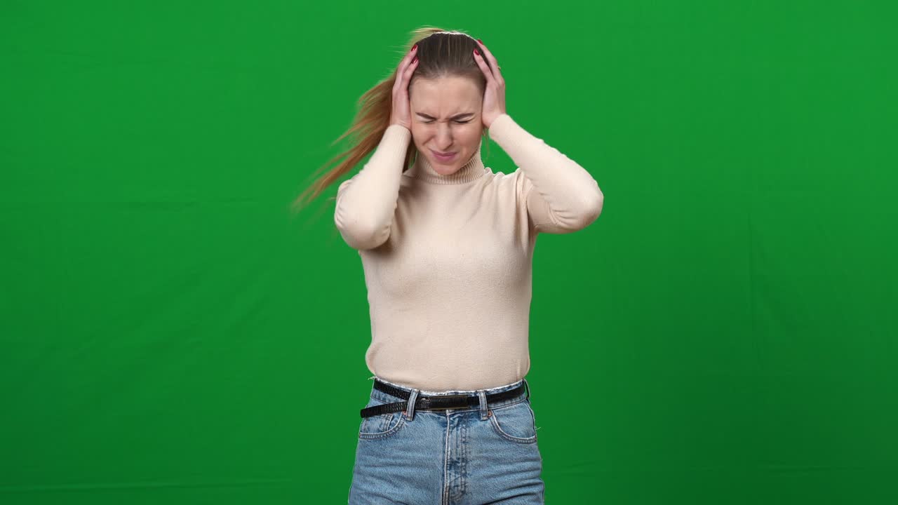손으로 귀를 닫고 머리를 흔들고 있는 짜증나는 여자가 녹색 스크린에서 소음으로 고통받는 짜증난 백인 젊은 여자의 초상화.