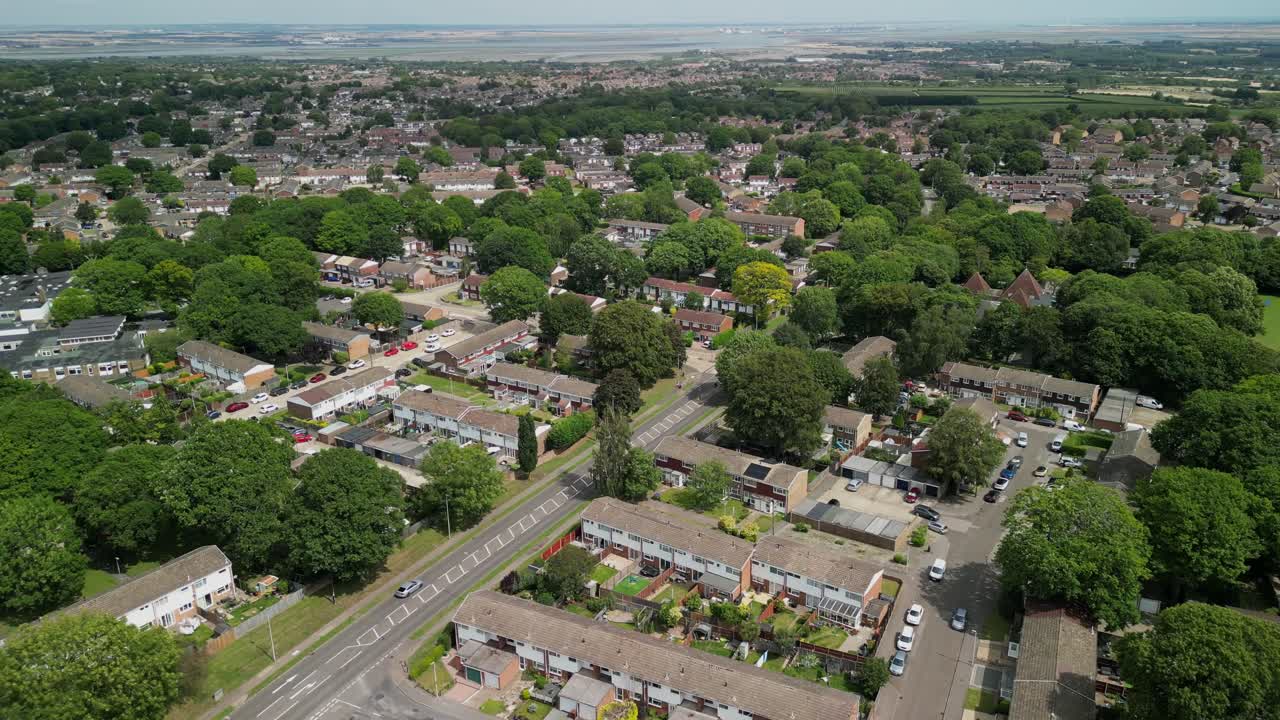 Drone flyover of Medway town with rows of rooftops and winding roads through greenery