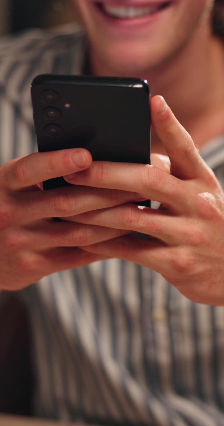Uomo sorridente che usa lo smartphone in un ambiente casual