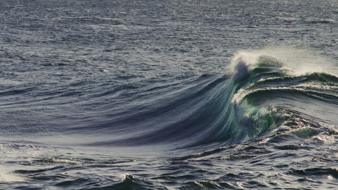 Gentle wave undulates over surface, consistent curl and foam trail under soft sunset sky