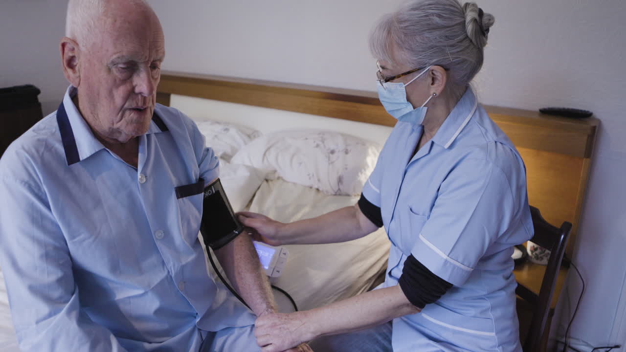 Nurse taking blood pressure of elderly man at home