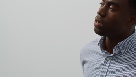 close up of young businessman in office looking at message with bad news on mobile phone and leans against wall looking unhappy and depressed