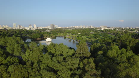 flying over the trees of ramat gan national park and revealing the lake in its center, it's a public meeting place for families, friends and barbecue