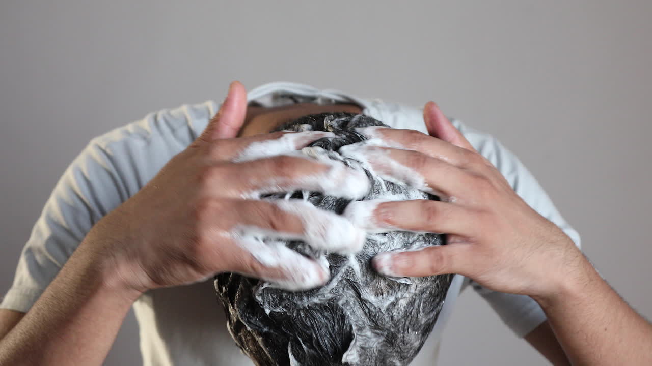 mano dell'uomo che pulisce i capelli con uno shampoo antiforfora a casa