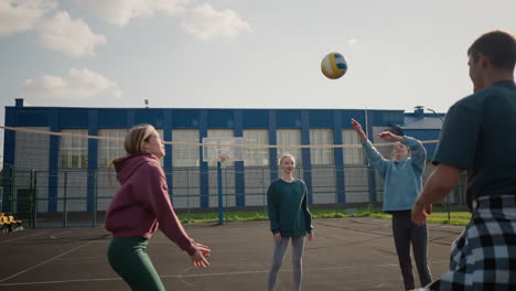 coach leads training session with three ladies passing volleyball between them on outdoor court, demonstrating teamwork and practice, with building and fence in background