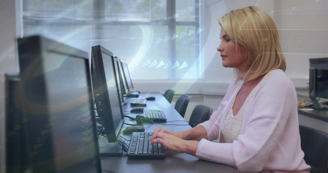 Reife Frau tippt am Labortisch, beugt sich vor, um Text zu lesen, während kreisförmige Grafiken auf Monitoren erscheinen
