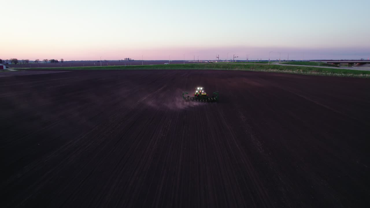 Vista aerea da dietro un trattore che ara un campo al crepuscolo