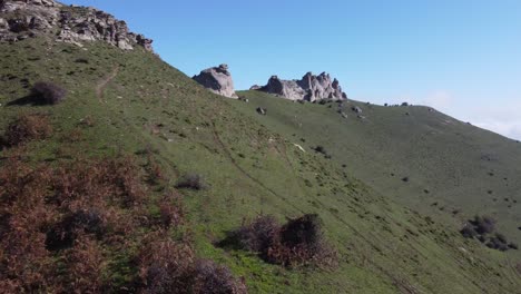 Vuelo-Bajo-A-Lo-Largo-De-La-Pendiente-De-Hierba-Montaña-Arriba-Hacia-Afloramientos-De-Roca-De-Granito