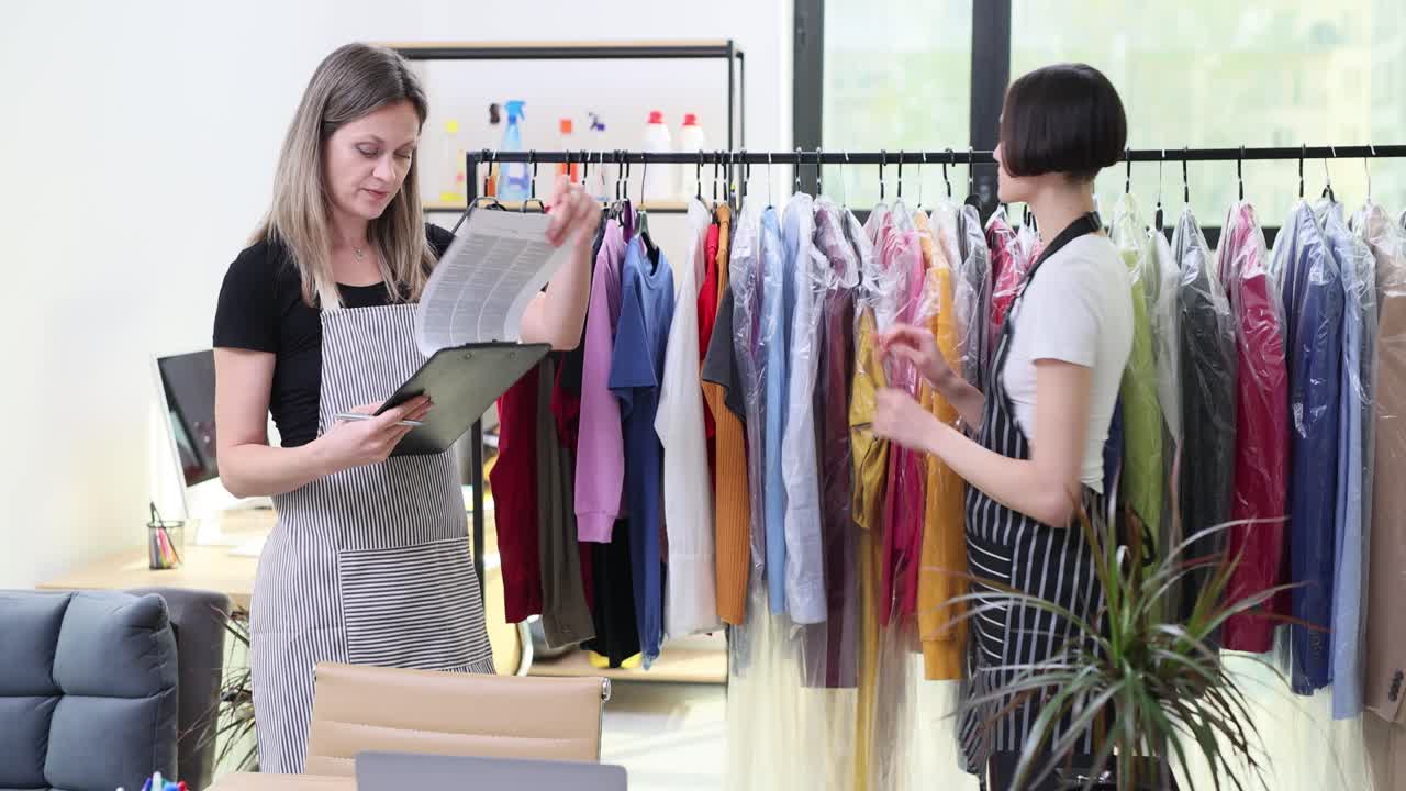 Due impiegate che controllano i vestiti puliti in una tintoria
