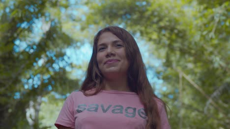 chica latina riendo y disfrutando de pie en un parque con árboles de bambú en el fondo