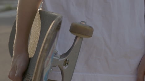 closeup on a skateboard held by a skater at his side