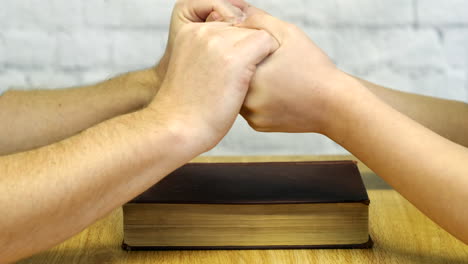 Primer-Plano-De-Un-Hombre-Parying-Con-Un-Hombre-Y-Una-Mujer-Con-Una-Biblia-En-Una-Mesa