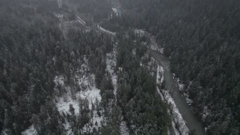 Stunning-aerial-drone-shot-of-the-snow-capped-Washington-Mountains-in-misty-fog,-with-a-river-running-through-it-winding-through-the-pine-trees,-no-people