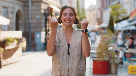 young woman shouting, celebrating success winning goal achievement good victory news in city street